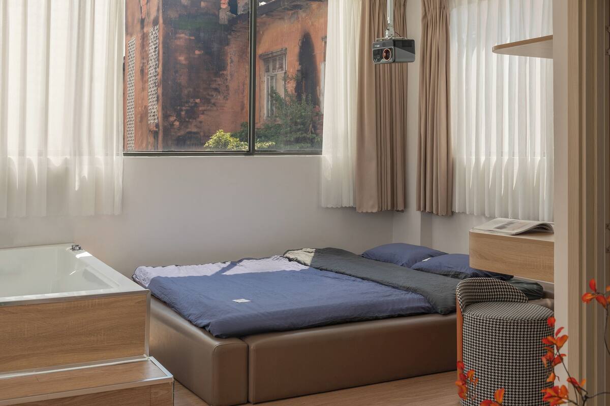 Une chambre moderne avec un grand lit, un bureau et une fenêtre avec des rideaux.