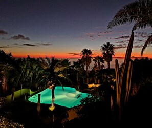 Ein Poolbereich mit Blick auf den Sonnenuntergang und Palmen.