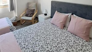 Habitación de hotel con una cama grande, una silla, un televisor y un ventanal con cortinas.