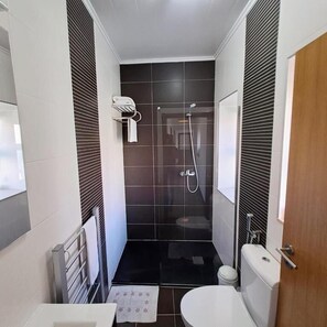 Une petite salle de bain comprenant une douche, des toilettes et un lavabo.