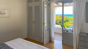 Een slaapkamer met een bed, een kledingkast en een balkon met uitzicht op zee.