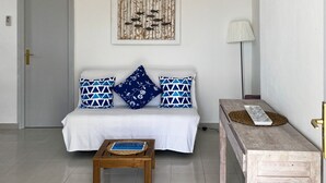 Een moderne woonkamer met een bank, een salontafel, een hanglamp en een wandkunstwerk.