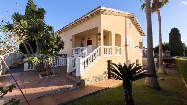 Un bâtiment à deux étages doté d’un balcon, d’un escalier et d’une pelouse bien entretenue agrémentée de palmiers.