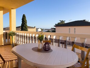 Un balcon avec une table, des chaises et des plantes en pot.