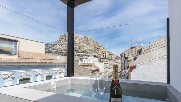 Un balcón con una botella de Moët & Chandon y dos copas, con vistas a un paisaje montañoso que incluye edificios.
