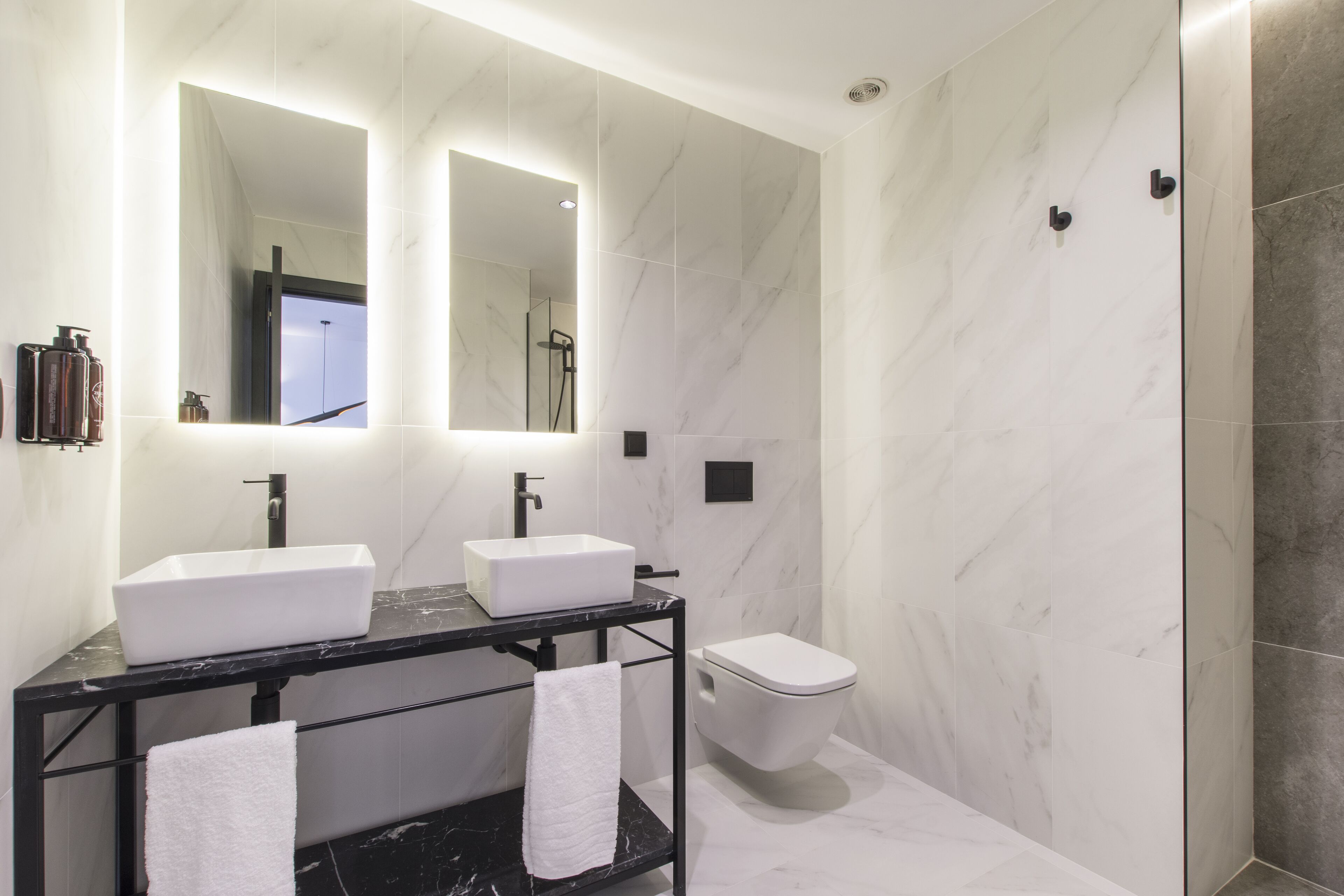 A modern bathroom with two sinks, a toilet, and a shower.