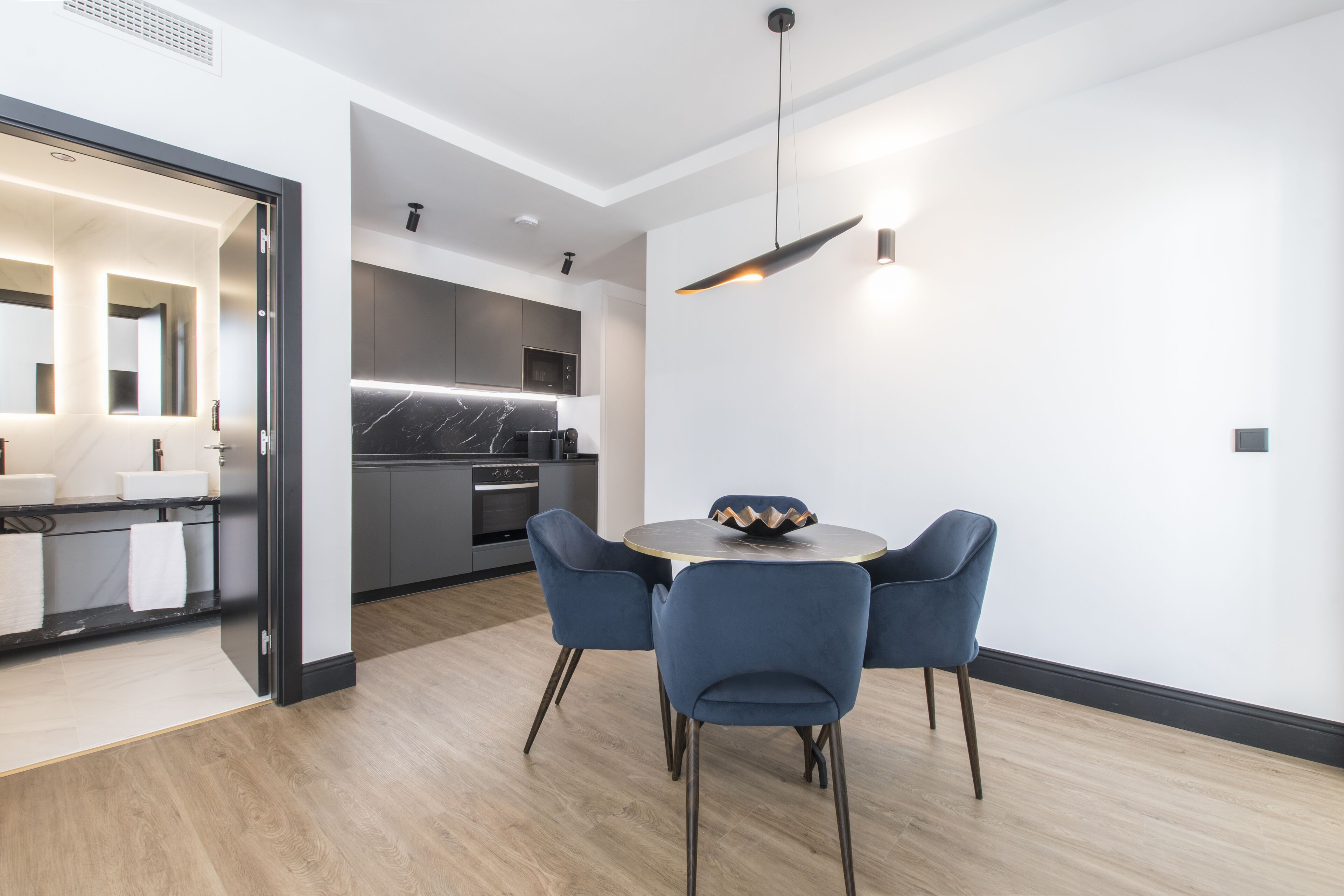 A modern kitchen with dark cabinets, a marble countertop, and a built-in oven.