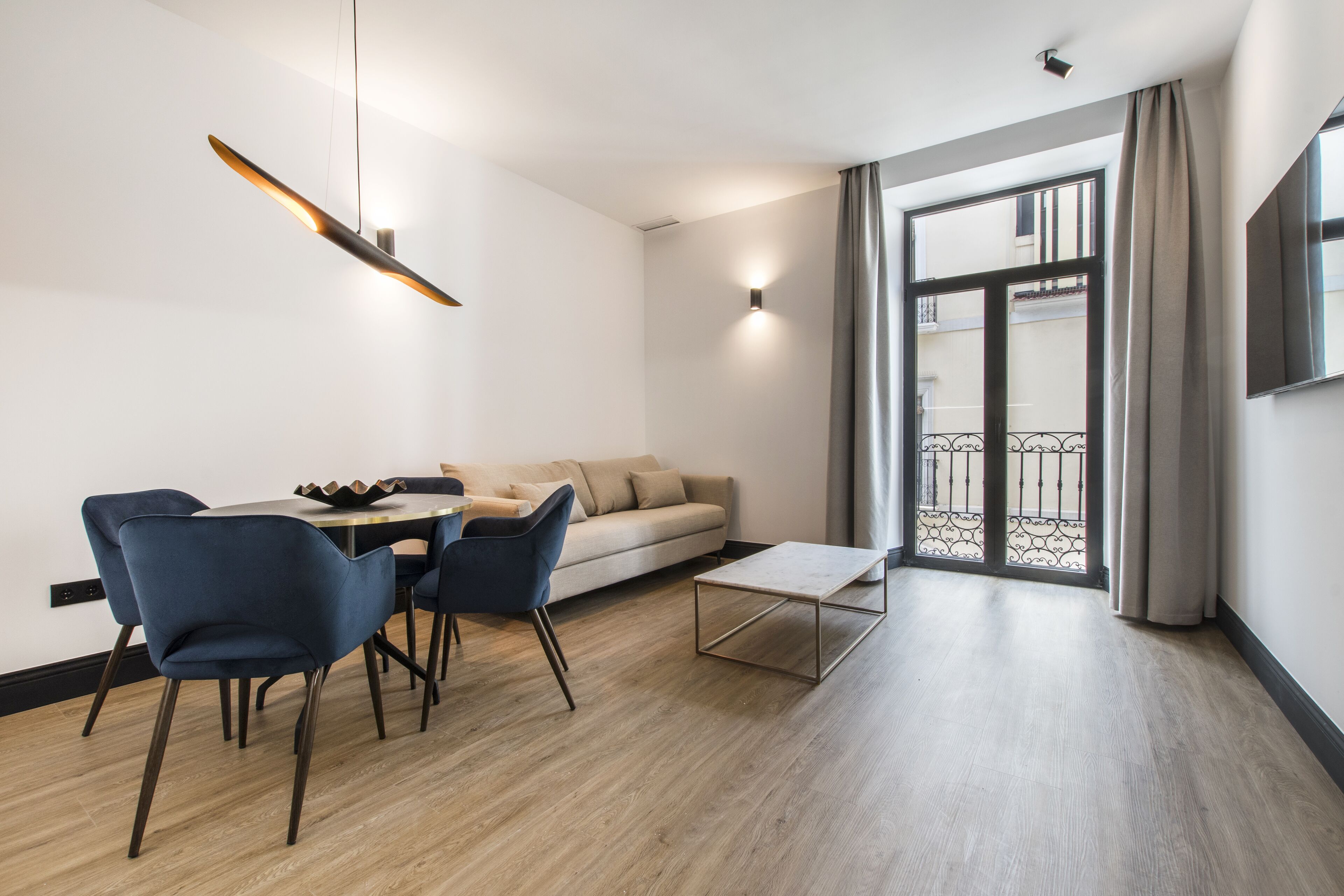 Una sala de estar moderna con un sofá, una mesa de comedor, sillas y una mesa de centro.