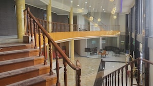 A spacious lobby with a curved staircase, multiple seating areas, and a high ceiling with recessed lighting. - Blue Hotel & Resort (Porac)