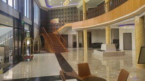 A spacious lobby with a grand staircase, polished marble floors, and a high ceiling with modern lighting fixtures. - Blue Hotel & Resort (Porac)