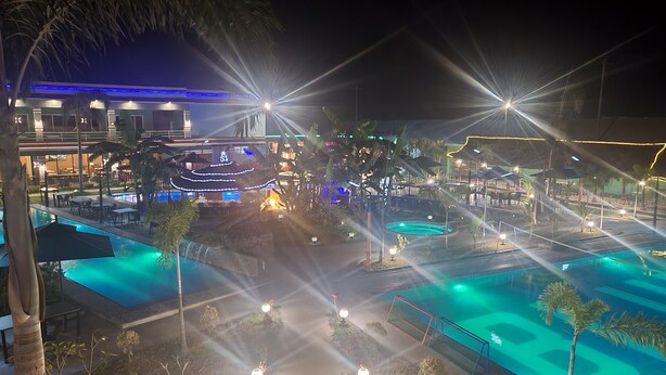 A resort pool area with multiple pools, palm trees, and outdoor seating. - Blue Hotel & Resort (Porac)