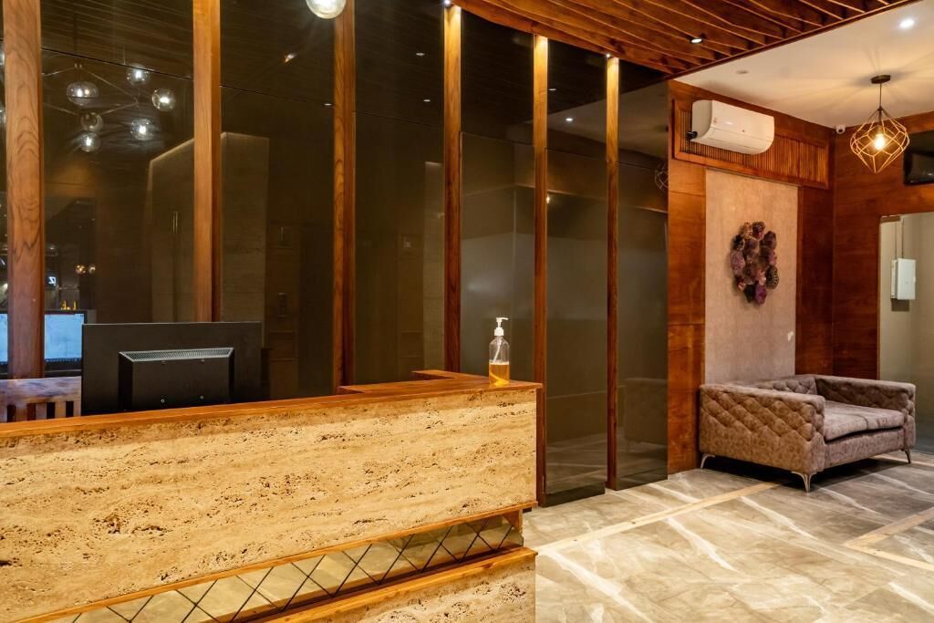 Un área de recepción con un mostrador de madera, un sillón acolchado y un aire acondicionado de pared.