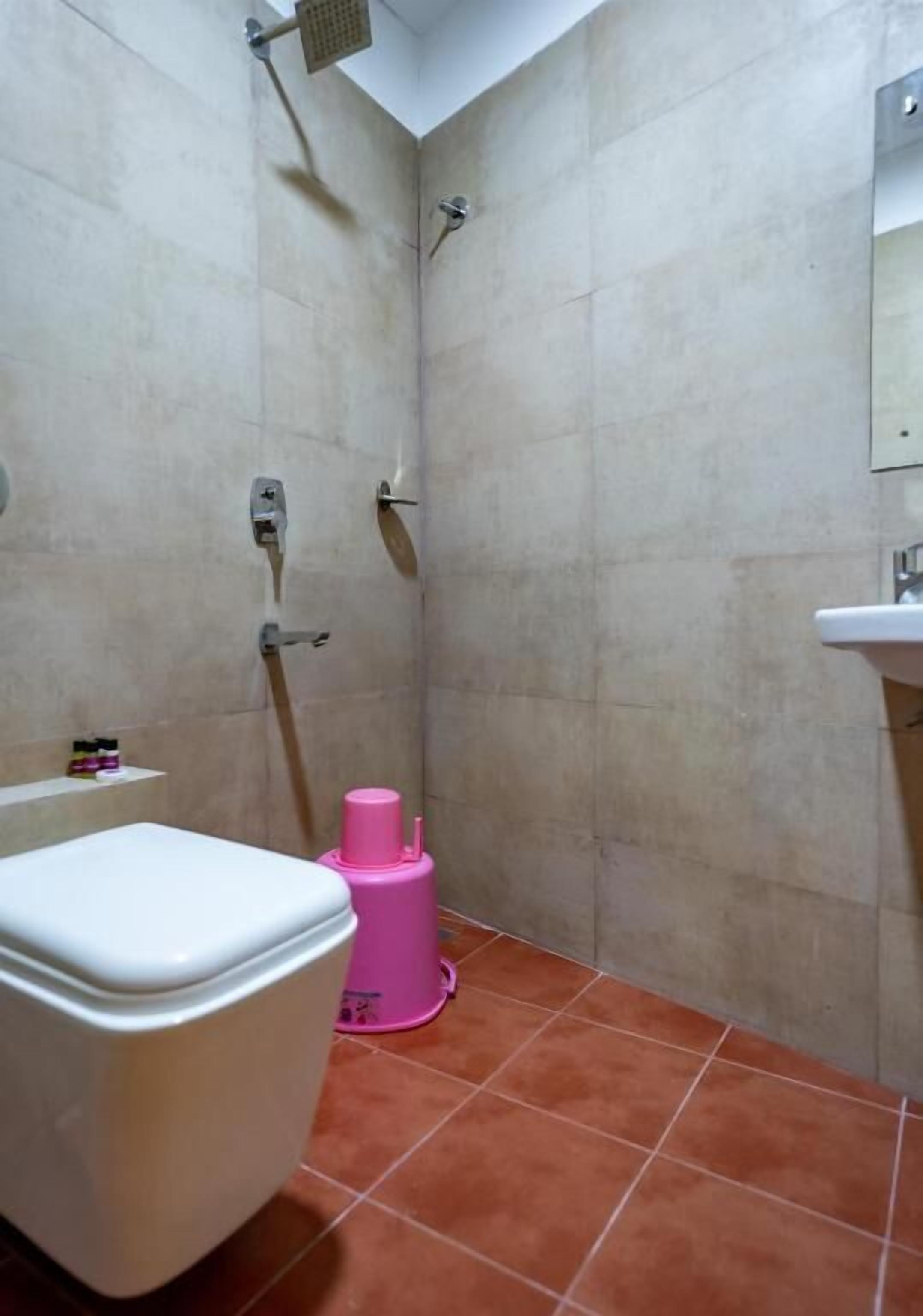A small bathroom with a toilet, a shower, and a sink.