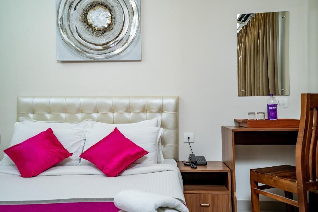 A hotel room with a bed, a desk, a chair, a telephone, and a mirror.