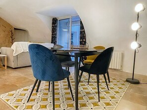 A dining area with a table and chairs, a patterned rug, and a floor lamp.