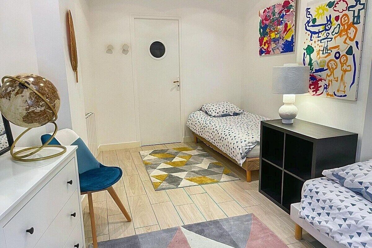 Quarto com uma cama, uma escrivaninha, uma cadeira, um globo e obras de arte na parede.