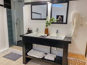 Et moderne badeværelse med to håndvaske, en bruser, et håndklædestativ og et spejl.