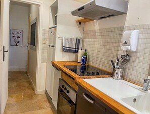 A compact kitchen with a wooden countertop, a built-in oven, a sink, and a tiled backsplash.