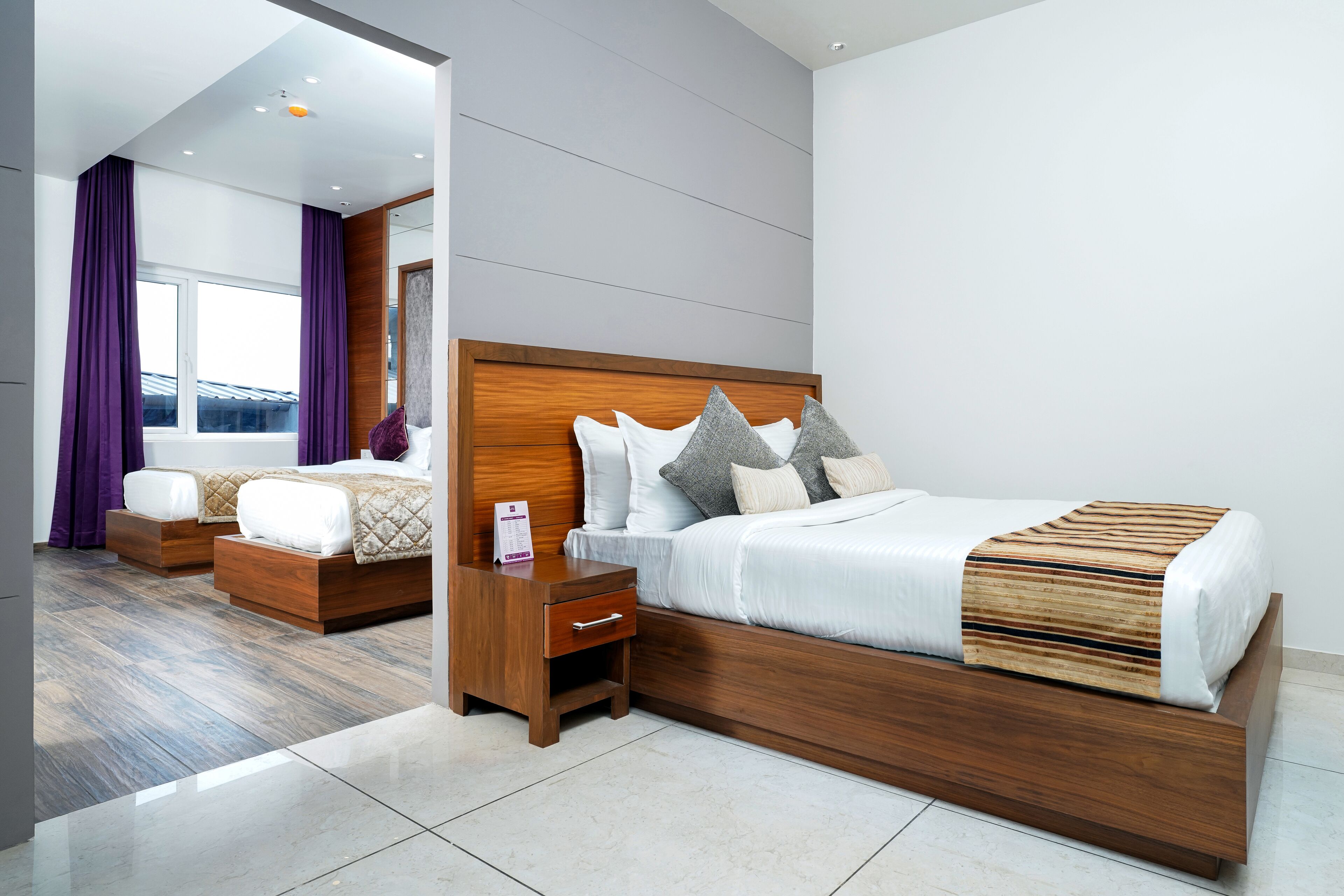 A modern bedroom with a large bed, a nightstand, and a dresser.