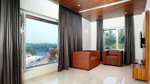Amplia habitación con un ventanal grande, dos sofás de cuero, un mostrador de recepción de madera y vistas a la carretera y vegetación.