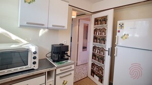 A compact kitchen with a microwave, coffee maker, and a refrigerator with a decorative magnet.