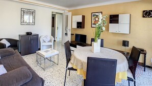 A modern living room with a dining area, a sofa, a coffee table, and a TV.
