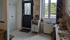 A room with a black door, white cabinets, a radiator, a window with curtains, and a small wooden table. - Rustic old mill with garden, WIFI and parking, pets allowed (Saint-Mary)