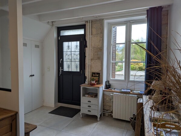 A room with a black door, white cabinets, a radiator, a window with curtains, and a small wooden table. - Rustic old mill with garden, WIFI and parking, pets allowed (Saint-Mary)