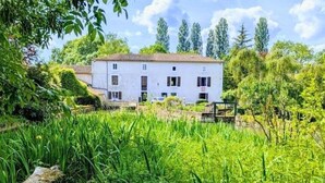 A white building with a red roof, surrounded by lush greenery and trees. - Rustic old mill with garden, WIFI and parking, pets allowed (Saint-Mary)