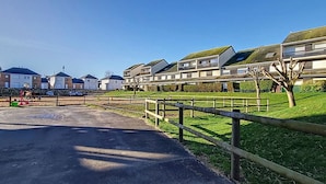 Et boligområde med moderne huse, en anlagt sti og et indhegnet rideområde.