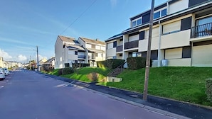 En villavej med moderne, toetagers huse, klar himmel og velholdt græsplæne.