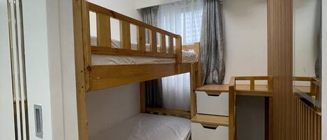 A bunk bed room with a desk and storage, an air conditioning unit, and a ceiling light fixture.