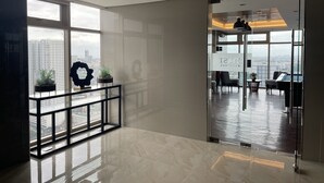 Un espace de bureau moderne doté d’une cloison en verre, offrant une vue sur la ville, et comprenant un espace d’accueil avec un bureau et des chaises.