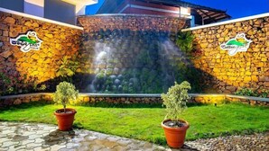 A stone wall with a water feature and potted plants. - Nexstay Coffee Grove Resort (Chikkamagaluru)