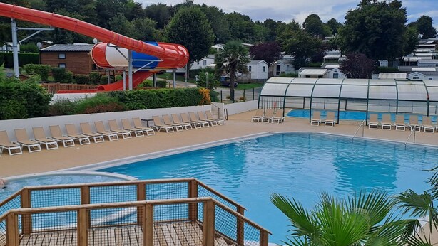 A swimming pool with a water slide and lounge chairs. - "mobil-home Sweet Home" : 32 m² 3 Chambres, 6 Personnes, au Calme Avec Jardin (Houlgate)