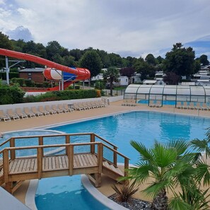 A swimming pool with a water slide and lounge chairs. - "mobil-home Sweet Home" : 32 m² 3 Chambres, 6 Personnes, au Calme Avec Jardin (Houlgate)