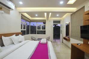 Una habitación de hotel con cama, televisión, balcón y ventana con vistas.
