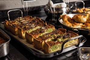 A buffet with various dishes, including a large tray of baked items and other food options. - Almond Hotel – Adults Only (Mateh Yehuda)