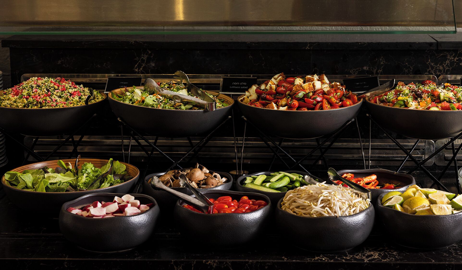 Un bufé con diversos platos, entre ellos ensaladas, verduras y carnes.