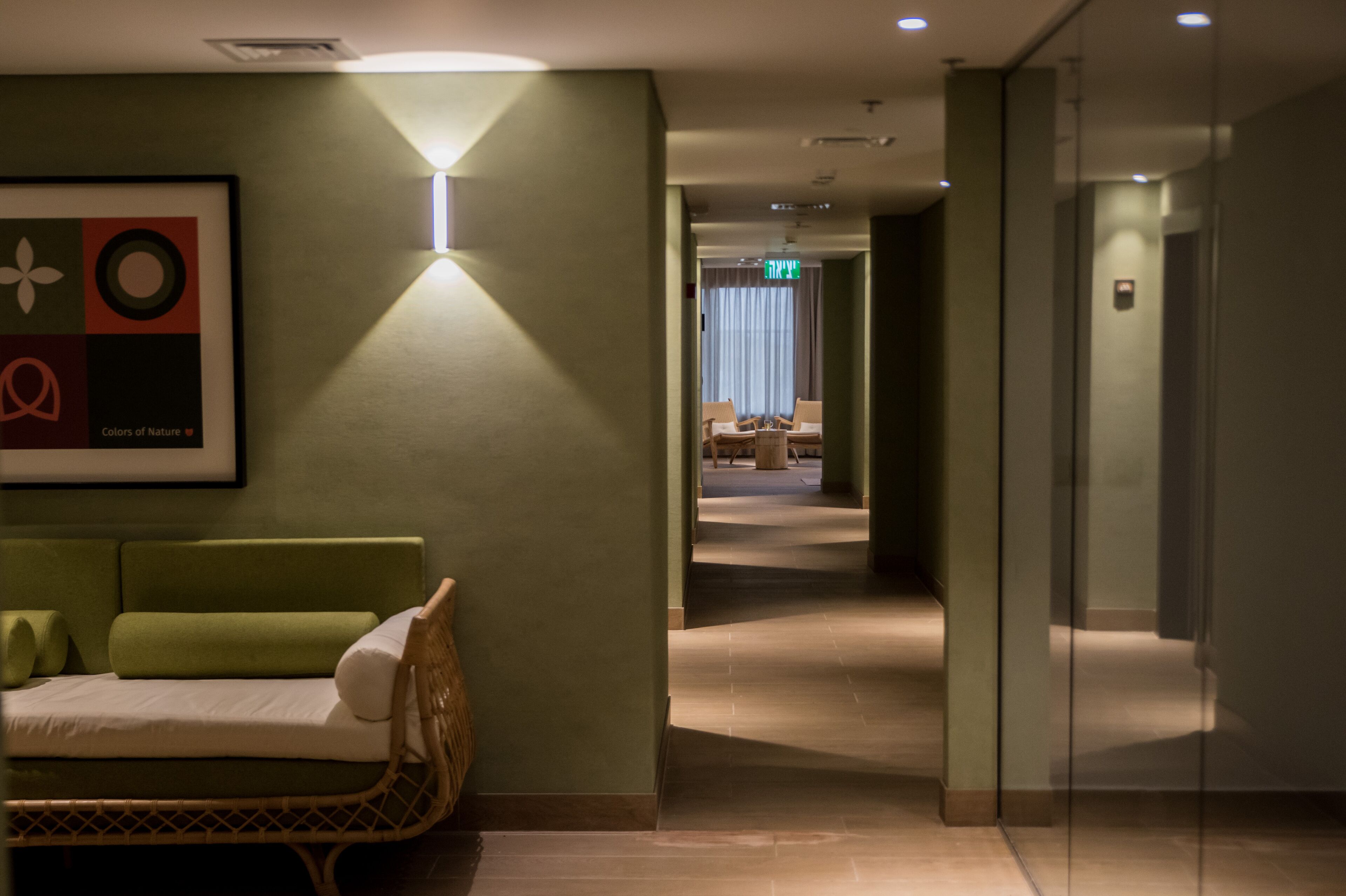 A hotel lobby with a green sofa, a framed artwork, and a glass partition.