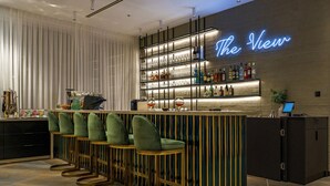 A bar area with a neon sign reading "The View," bar stools, shelves with bottles, and a cash register. - Almond Hotel – Adults Only (Mateh Yehuda)
