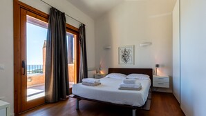 Un dormitorio con cama, mesitas de noche, una ventana con cortinas, vistas al exterior y una obra de arte en la pared.