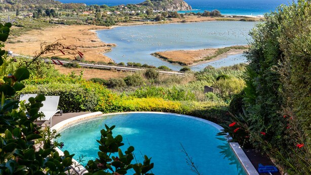 Una piscina con vistas a un paisaje costero, que incluye una colina con una torre y un puente.