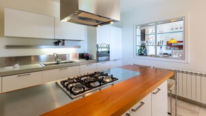 Cocina moderna con una isla central, electrodomésticos de acero inoxidable y una ventana con vistas a un área de bar.