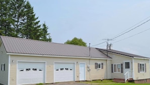 A single-story house with a garage, a front porch, and a metal roof. - On Long Lake with Direct Access to Trails-L & R Lakeside Rentals  (Sinclair)