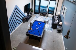 A modern living room with a pool table, a flat-screen TV, and a seating area with a view of the outdoors. - 5Mile to Disney • Gym • Pool Table • Pet Ok • Parking (Santa Ana)