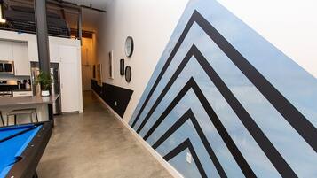 A pool table in a room with a modern kitchen area and a large wall mural.
