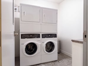 A laundry room with two stacked front-loading washing machines and a dryer.