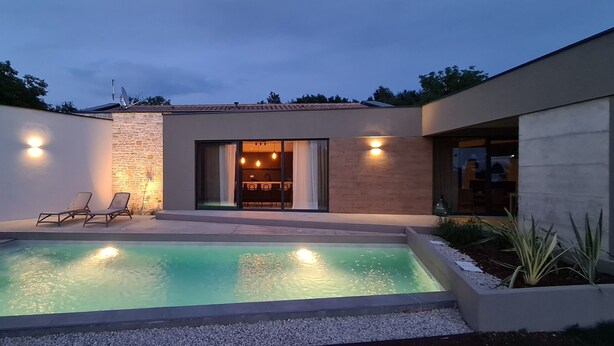 Une maison moderne dotée d’une piscine, d’un espace salon extérieur et d’un coin repas.