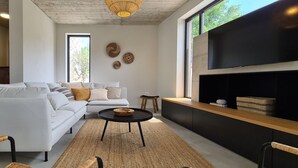 Un salon moderne avec un canapé blanc, une table basse noire et un grand téléviseur.